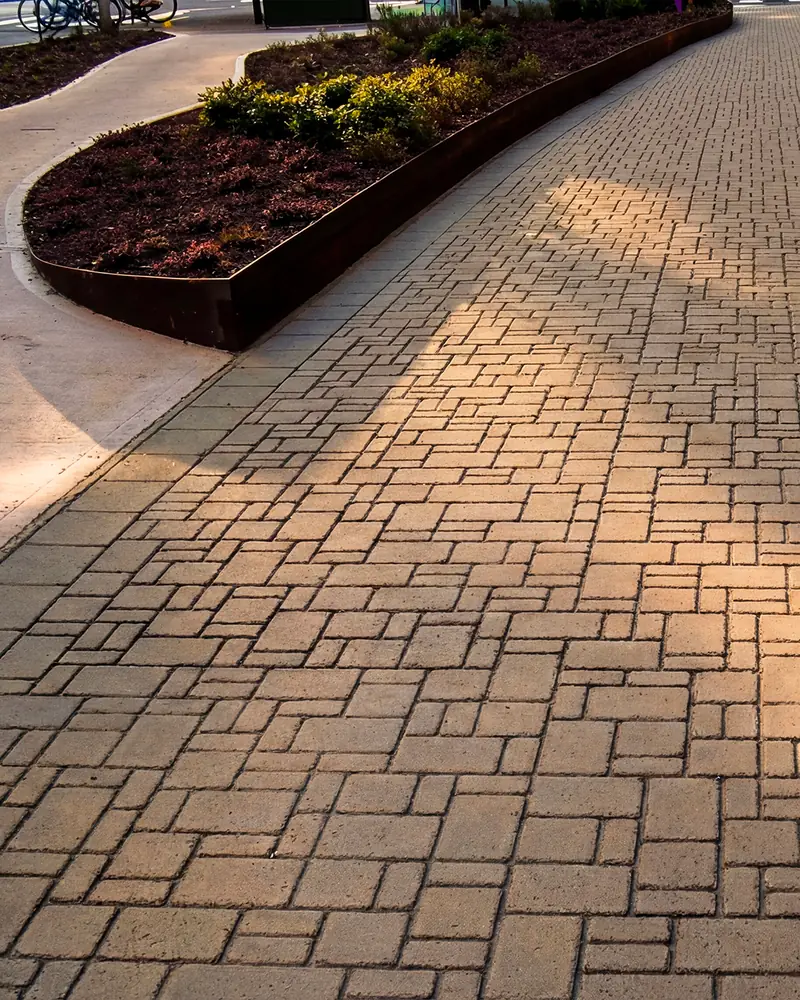 Percorso pedonale in asfalto stampato effetto mattone, luce radente